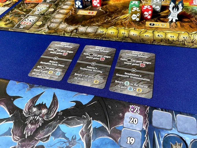 the board game Shadow Kingdoms of Valeria with three 'ancient spell' cards in front of one of the player boards.
