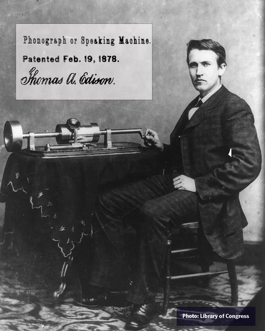 Black and white photograph of Thomas Edison with an early prototype of the phonograph, dated February 19, 1878. Edison is standing next to the device, placed on a table. Photo: Library of Congress.