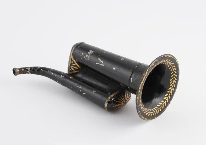 A black hearing aid with gold decoration, painted around the bell and on the bends