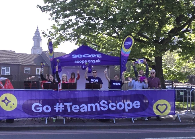 A Team Scope cheerpoint at the London Marathon with people wearing Scope t shirts and cheering with their hands in the air.