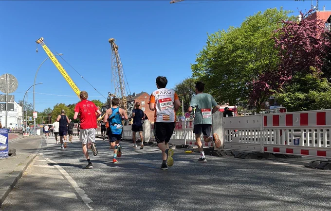 Läufer auf der Marathonstrecke, im Hintergrund das Banner „Der Bau der neuen U5? Läuft!“