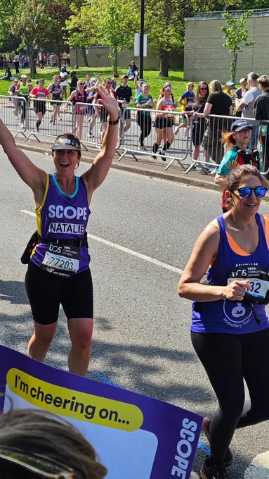 Team Scope runner Natalie smiling and cheering as she runs past the Scope cheerpoint