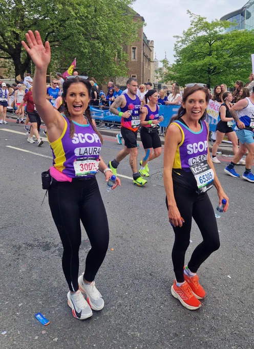 Team Scope runners Laura and Clare smiling and running past the Scope cheerpoint
