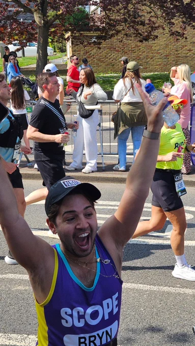 Team Scope runner Bryn running past the Scope cheering point with his arms up and cheering