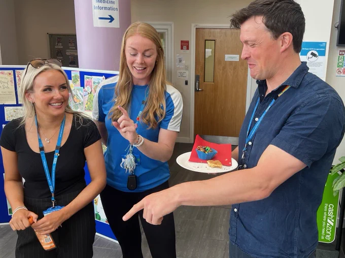 two female and one male staff member enjoying cake 