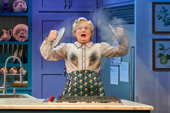 Mrs Doubtfire looks shocked as she holds pan lids in the air!