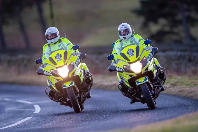 Two Police Scotland Motorcycle officers riding side by side on marked police motorcycles