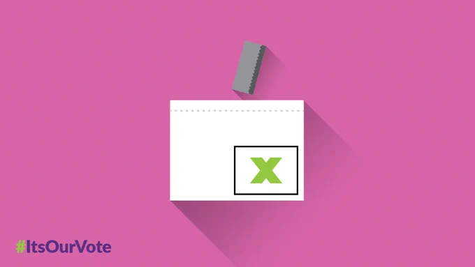 A folded ballot going into a ballot box.