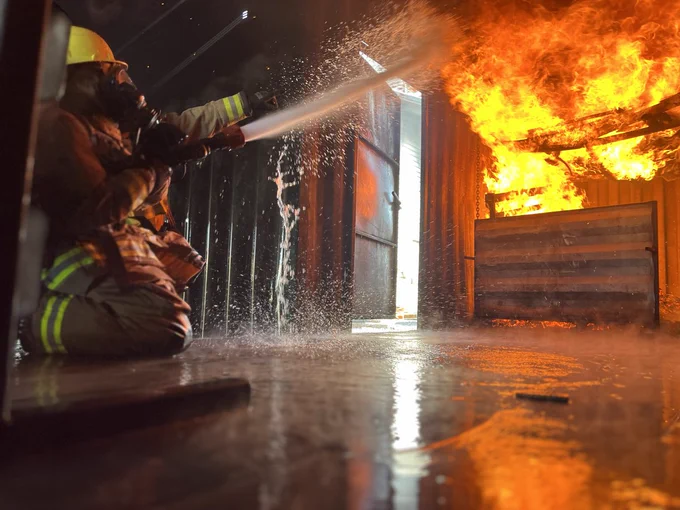 Fire fighter holds hose at fire 