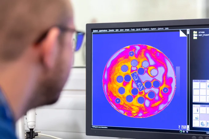 Researcher looking at colourful circular structure on computer imaging.