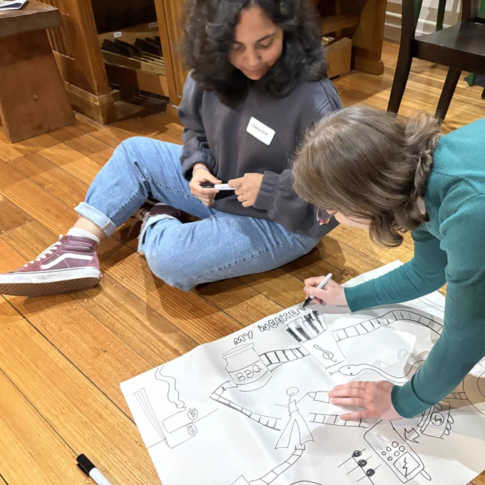 Closer view of photo 2 showing two of the musicians working on the score. A mobile phone, a treble clef and a jar of BBQ sauce can also be seen on the drawing.