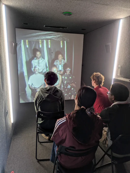Four people (who are based in Hanover, NH) sit in a room video chatting with five people (who are based in Kigali, Rwanda) 