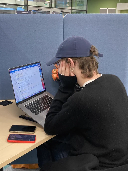 A person sitting at a library work station and working on a laptop