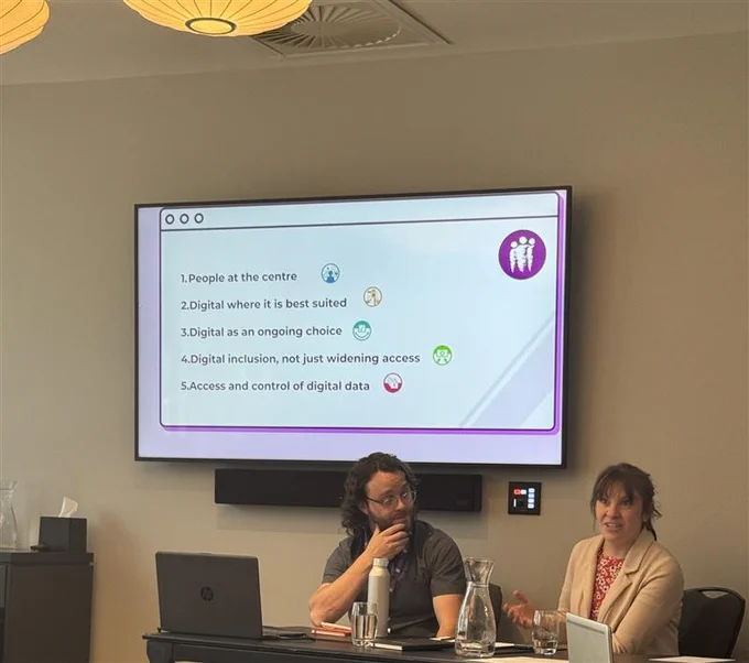 Cillian and Louise sat in front of a screen showing the Digital Human Rights Principles: 
1. People at the centre 
2. Digital where its best suited 
3. Digital is an ongoing choice 
4. Digital inclusion, not just widening access 
5. Access and control of digital data 