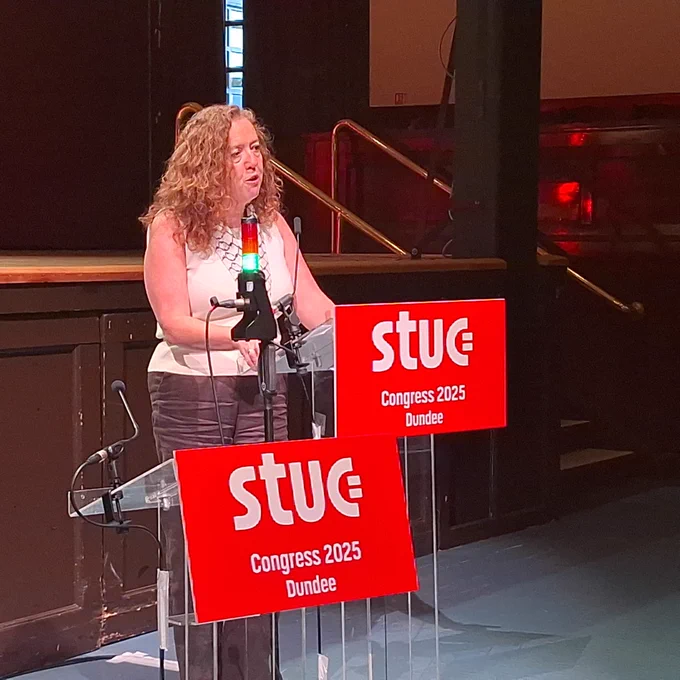 An image of Fran speaking at the podium 