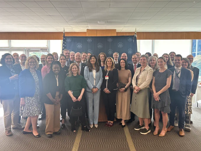 Deputy Assistant Secretary for Science, Technology, and Space Affairs Rahima Kandahari stands in the center of a large group for a group photo. The backdrop includes a blue banner with the Department of State logos and the American flag.





