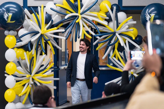 Victor Gomez enters a room filled with blue, white, and yellow balloons