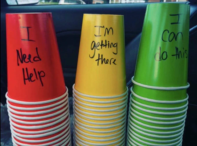Image shows stacks of red, yellow and green paper cups, bearing the phrases "I need help," "I'm getting there" and "I can do this," respectively.