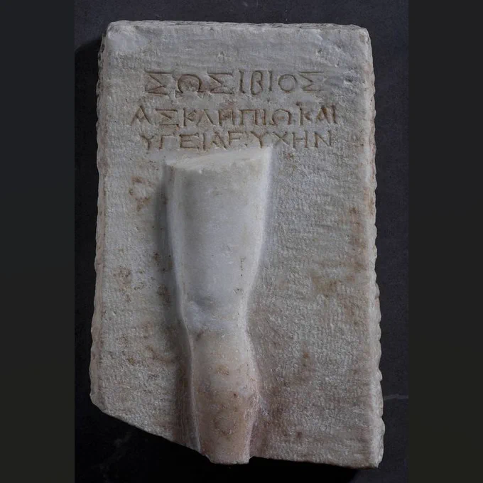 Marble plaque with Greek inscription and a disembodied leg