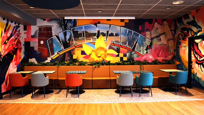 A photo of one of the incredible murals in the Global Lounge. The one in the centre includes the word Abertawe, a daffodil and buildings from both Swansea’s Singleton and Bay campuses. On the left is a Welsh dragon, and on the right is a Chinese dragon.