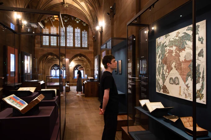 Visitors in the new collections gallery looking at a map in the foreground. 