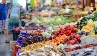 A farmers market with stalls full of colourful fresh veggies. 