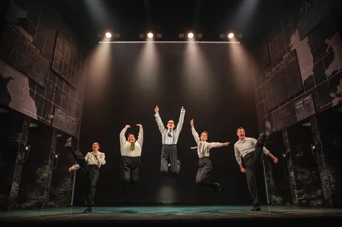 A photo showing five performers jumping on a stage