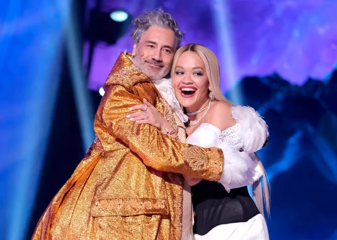 Taika Waititi holding Rita Ora in his Masked Singer Lucky Duck outfit