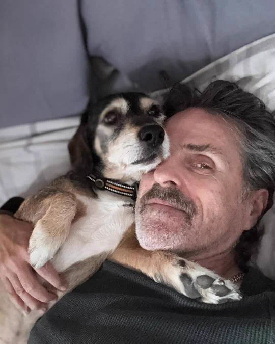 Con O'Neill lays holding his doc cooper, looking up at the camera
