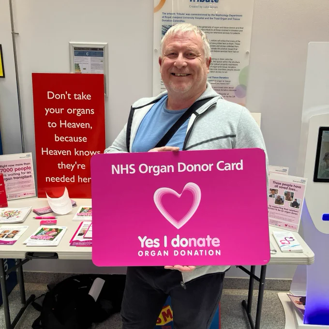 A photo of Gary, just after he signed up to the NHS Organ Donor Register. He is smiling and holding an oversized organ donor card which reads "Yes - I donate."