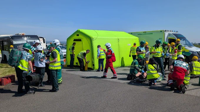 A number of emergency tents and numerous people in ambulance and other emergency service uniforms engaged in an exercise.