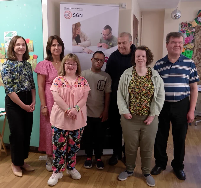 Four women and three men are smiling and standing in front of a pop-up banner with the 'In partnership with SGN logo' visible