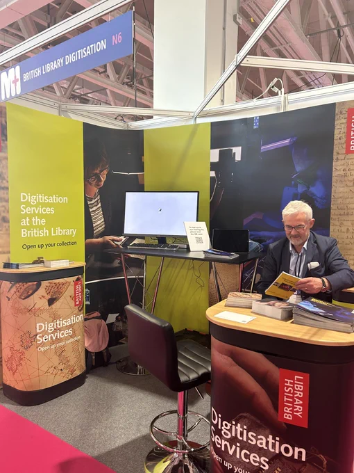 A photo of a stand at a trade show labelled ‘Digitisation Services’ at stand N6 with colourful banners.
