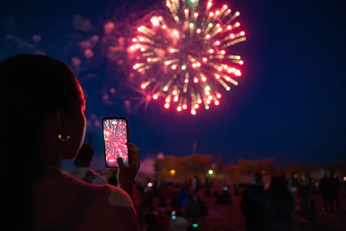 person taking photos of fireworks on phone