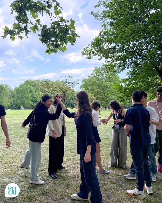 A photo of the International Public Speaking Competition participants getting to know each other, playing rounders in the park.