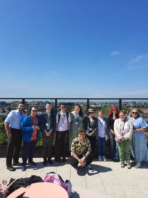 A group of TCPID students and staff with staff from LinkedIn standing outside on a terrace with a beautiful sunny blue sky visible behind them. 