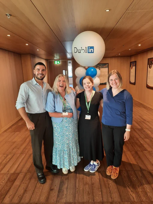 Two people from LinkedIn and two people from TCPID standing in front of a large display of blue and white balloons. 
