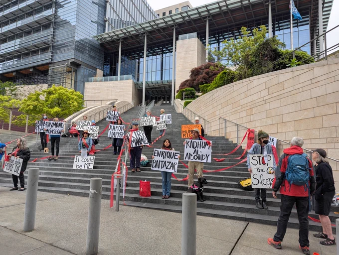People standing in front of city hall with signs with names