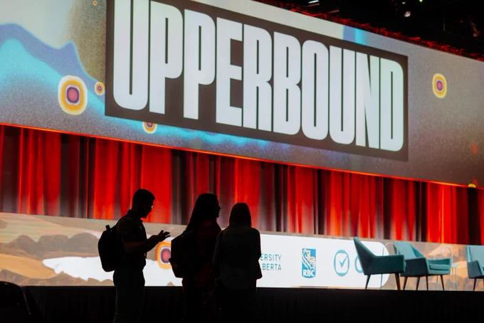 Attendees at Upper Bound stand silhouetted against a screen background