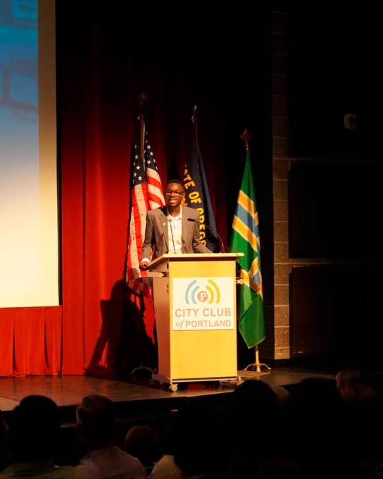 Photo of JJ Kunsevi standing behind the podium at Franklin High School during the Mayor Wilson State of the City event