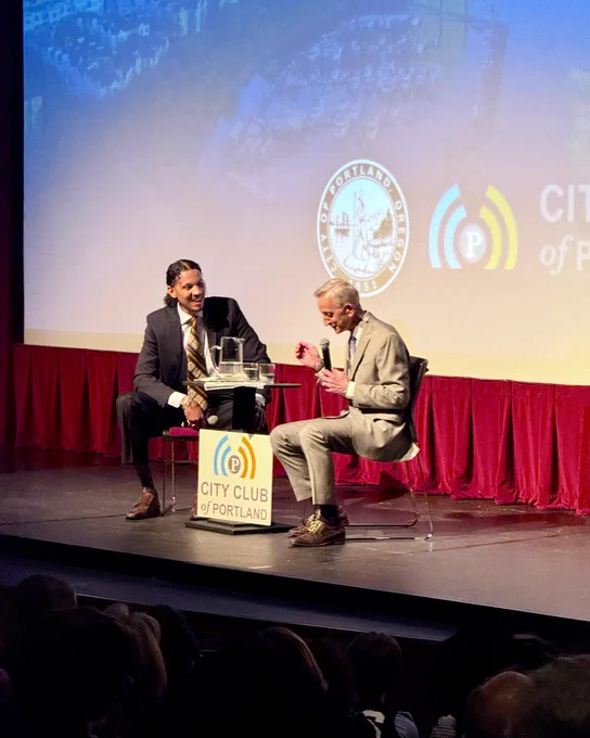 Photo of JT Flowers on stage with Mayor Wilson during the conversation portion of the State of the City, JT Flowers is laughing with Mayor Wilson on stage