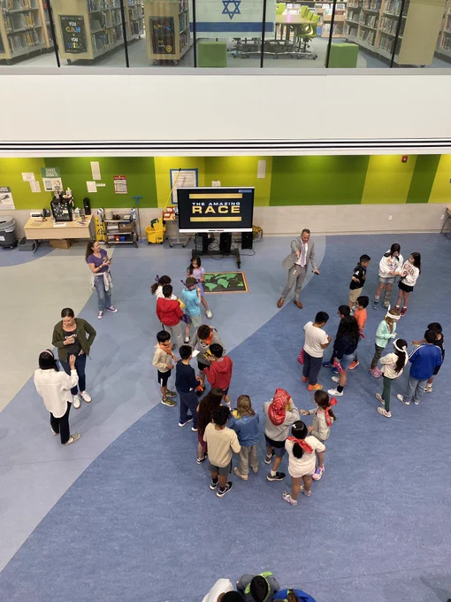 Student in a cafeteria with a sign that says the amazing race