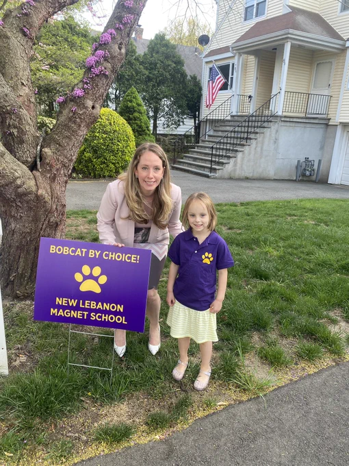Woman with young girl next to a sign that says bobcats by choice new Lebanon magnet school.