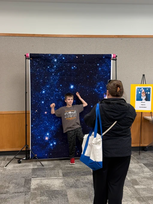 A kid being photographed in front of the Space background