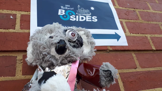 Droppy the #infosec cyborg dropbear in front of the sign to BSides Ballarat.