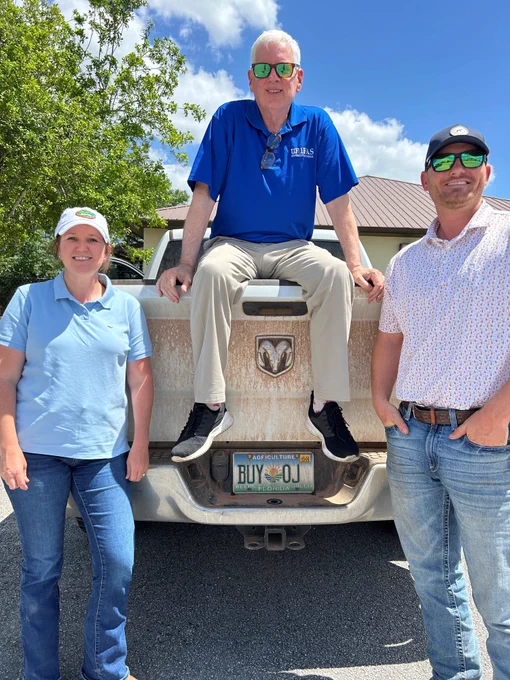 Myself sitting on the back of a truck with two citrus growers.