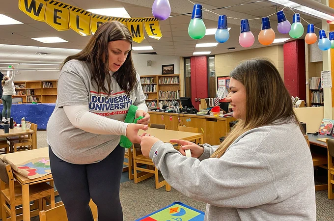 Kenzie Bole, right, works with another Education student, left as they decorate a classroom.