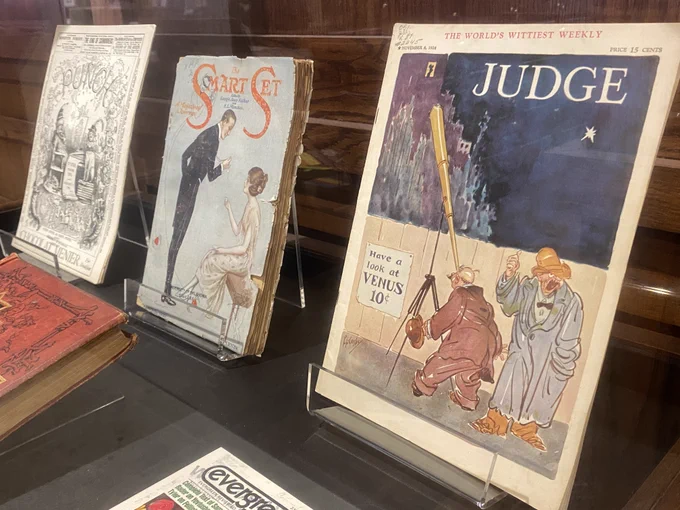 Photo of display case with several items, including three magazines (Punch, The Smart Set, and Judge).