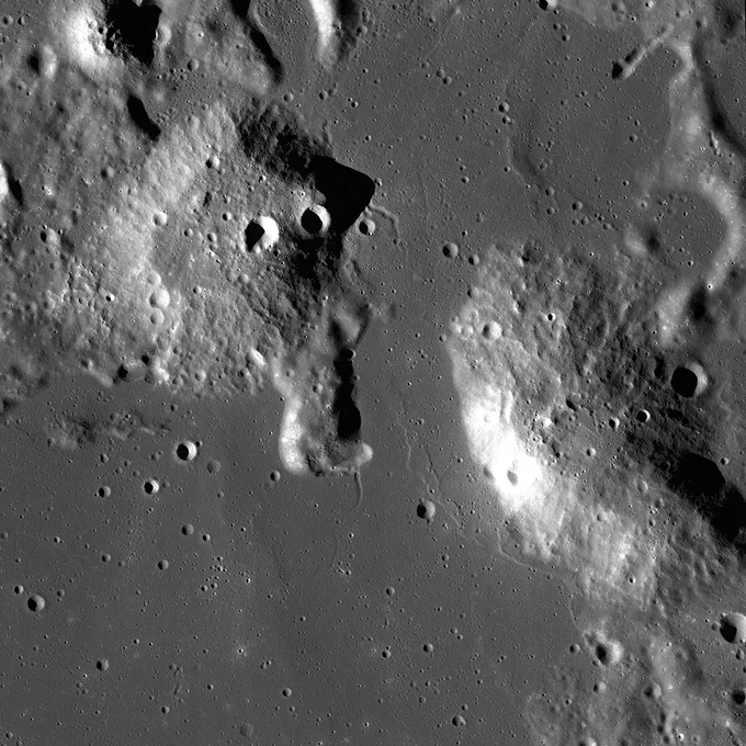 Orbital view of mountainous terrain on the Moon. The Gruithuisen Domes protrude from the surrounding lunar landscape and are pockmarked with craters.