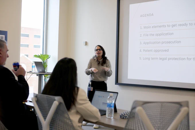 [ID: Pictured is a photo of people listening to a presentation during a workshop in the Day Family Research Lab.]